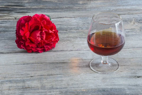 One glass of cognac and one red rose — Stock Photo, Image