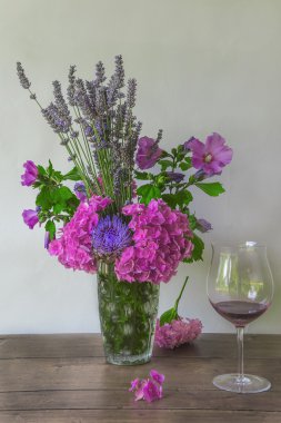Mor çiçekler (hydrangea, lavanta) ve kırmızı şarap oluşan