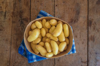 Damalı peçete ve ahşap ahşap üzerinde çiğ patates dolu sepet.