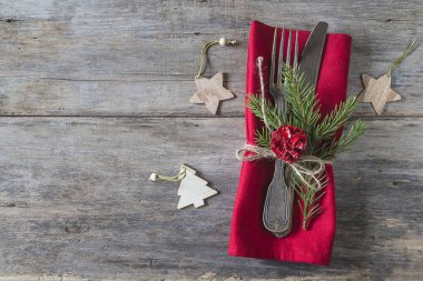 Noel bayramı yemeği için şenlik masası. Antika çatal ve bıçak, kırmızı peçete ve eski ahşap arka planda noel süslemeleri. Üst görünüm, boşluk kopyala