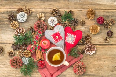 Noel tatili çay saati. Bir bardak limonlu çay, ahşap arka planda çeşitli koniler.