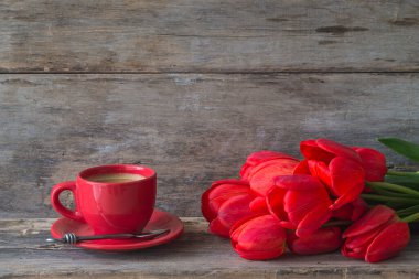 Tatilin tebrik kartı. Kırmızı kahve ve bir sürü kırmızı lale boyasız, ahşap arka planda. Metin için boşluk