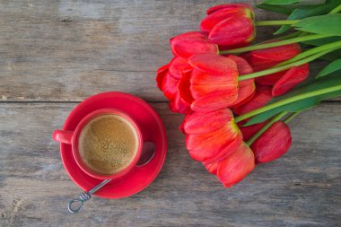 Tatilin tebrik kartı. Kırmızı kahve ve bir sürü kırmızı lale boyasız, ahşap arka planda. Üst görünüm