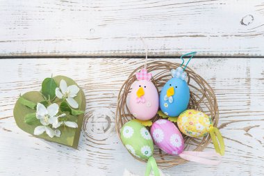 Mutlu Paskalya bayramı tebrik kartları. Paskalya yumurtalı sepet ve beyaz renkli ahşap arka planda elma çiçeği olan hediye kutusu şeklinde kalp. Metin için boşluk, üst görünüm