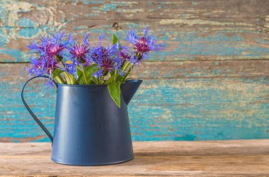 Mavi sürahide mavi çiçek buketi Eski mavi boya ahşap arka planda