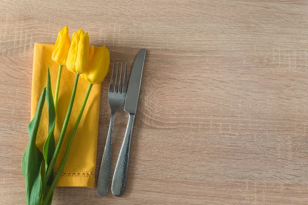 春假地点设置 黄色餐巾上的黄色郁金香束 免版税图库图片
