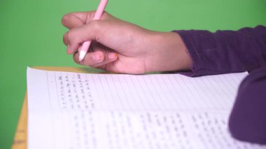 Kızın eli yeşil arkaplanlı bir kitap yazıyor. Seçilene odaklan