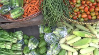 Geleneksel pazarda bambu sepetlerinde çeşitli sebzeler. Mısır, domates, uzun fasulye, havuç, salatalık var.