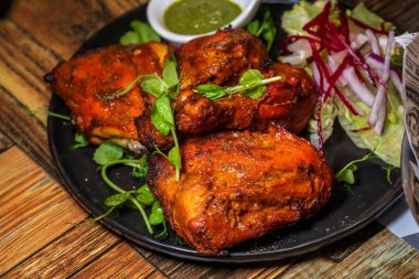 Parlak kırmızı, dumanlı ve baştan çıkarıcı kokulu Hint kızarmış tavuğu, kıtır marul ve özel yeşil sosla çiftleştirilmiş, güçlü bir görsel cazibe ve egzotik bir aşçılık deneyimi sunar..