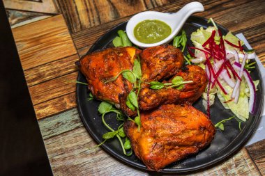 Parlak kırmızı, dumanlı ve baştan çıkarıcı kokulu Hint kızarmış tavuğu, kıtır marul ve özel yeşil sosla çiftleştirilmiş, güçlü bir görsel cazibe ve egzotik bir aşçılık deneyimi sunar..