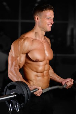 Spor salonunda egzersiz yapan yakışıklı kaslı vücut geliştirmeci erkek