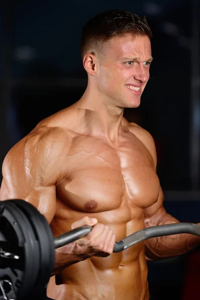 Guapo musculoso culturista hombre haciendo ejercicios en el gimnasio — Foto de Stock