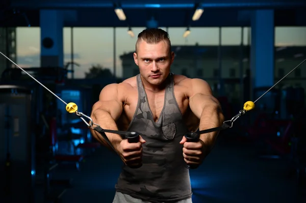 Bonito musculoso fisiculturista homem fazendo exercícios em gy — Fotografia de Stock