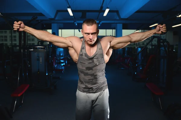 Bonito musculoso fisiculturista homem fazendo exercícios em gy — Fotografia de Stock