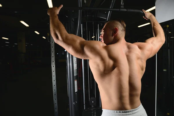 Bonito musculoso fisiculturista homem fazendo exercícios em gy — Fotografia de Stock