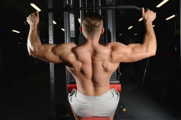 Bonito musculoso fisiculturista homem fazendo exercícios em gy — Fotografia de Stock