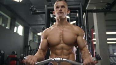 Beyaz tenli atletik adam kaslarını şişiriyor. Güçlü vücut geliştirici, karın kasları, trisepsleri, göğsü ve omuzları var. Fitness ve vücut geliştirme konsepti