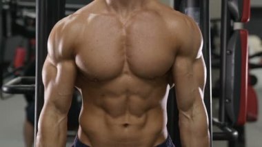 Beyaz tenli atletik adam kaslarını şişiriyor. Güçlü vücut geliştirici, karın kasları, trisepsleri, göğsü ve omuzları var. Fitness ve vücut geliştirme konsepti