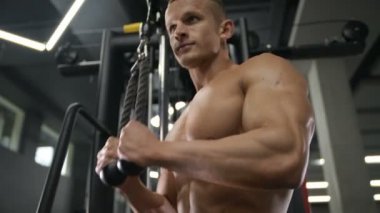 Beyaz tenli atletik adam kaslarını şişiriyor. Güçlü vücut geliştirici, karın kasları, trisepsleri, göğsü ve omuzları var. Fitness ve vücut geliştirme konsepti