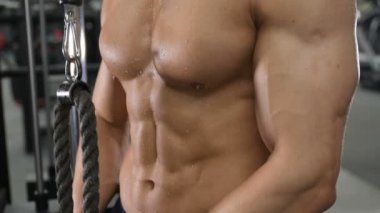 Beyaz tenli atletik adam kaslarını şişiriyor. Güçlü vücut geliştirici, karın kasları, trisepsleri, göğsü ve omuzları var. Fitness ve vücut geliştirme konsepti