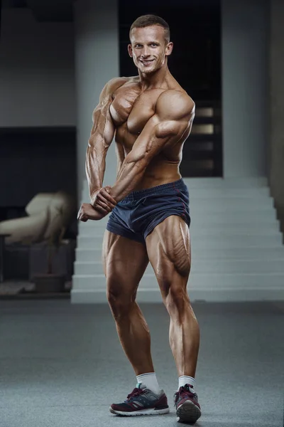 Caucasian power athletic man training pumping up leg quadriceps muscles. Strong bodybuilder with six pack, perfect abs, triceps, chest, shoulders in gym. Fitness and bodybuilding concept