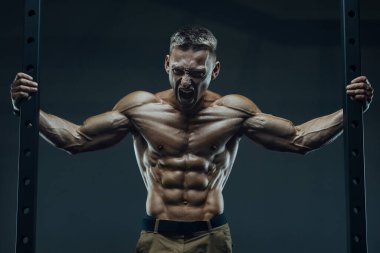 Öfke Çığlığı. Spor salonunda karın kasları çalışırken çığlık atan beyaz tenli güçlü bir sporcu. Fitness, vücut geliştirme ve sağlık hizmeti kavramı