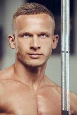 Spor salonundaki yakışıklı bir adamın yakın plan portresi. Beden eğitiminde altı kaslı göğsü ve omuzları olan güçlü bir vücut geliştirici. Fitness, vücut geliştirme ve egzersiz konsepti