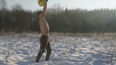 Fitness adamı kışın açık havada kaslarını kettlebell ile şişiriyor. Sağlık, spor ve sertleştirme konsepti