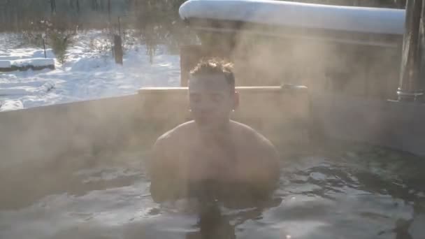 雪の降る冬には露天風呂でハンサムな男が蒸し風呂に入る スポーツ 健康と硬化の概念 — ストック動画