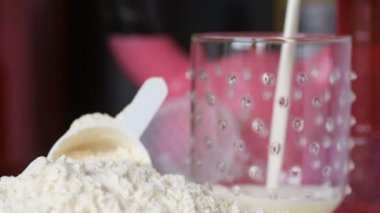 Protein tozu ve ölçüm kepçesi kavanozun üzerinde ve sallanan şişe arka planında. Vücut geliştirme, fitness ve spor salonu yaşam tarzı. Spor, sağlık ve beslenme konsepti