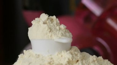 Protein tozu ve ölçüm kepçesi kavanozun üzerinde ve sallanan şişe arka planında. Vücut geliştirme, fitness ve spor salonu yaşam tarzı. Spor, sağlık ve beslenme konsepti