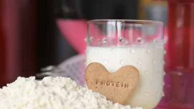 Protein tozu ve ölçüm kepçesi kavanozun üzerinde ve sallanan şişe arka planında. Vücut geliştirme, fitness ve spor salonu yaşam tarzı. Spor, sağlık ve beslenme konsepti