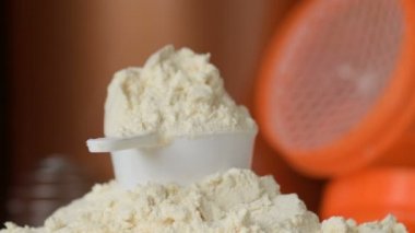 Protein tozu ve ölçüm kepçesi kavanozun üzerinde ve sallanan şişe arka planında. Vücut geliştirme, fitness ve spor salonu yaşam tarzı. Spor, sağlık ve beslenme konsepti