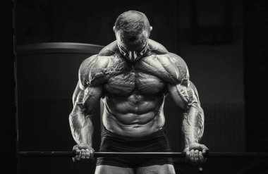 Vücut geliştirici kasları şişiriyor vücut geliştirme egzersizi yapıyor ve sağlıklı bir konsept geliştiriyor. Vücut geliştiren adamlar spor salonunda çıplak vücut egzersizleri yapıyor. Yakışıklı, güçlü, atletik sert adam.