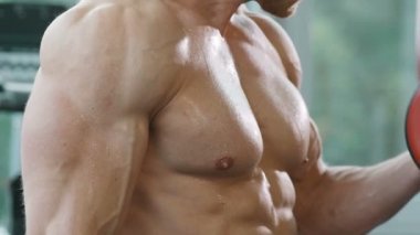 Beyaz tenli atletik adam kaslarını şişiriyor. Güçlü vücut geliştirici, karın kasları, trisepsleri, göğsü ve omuzları var. Fitness ve vücut geliştirme konsepti