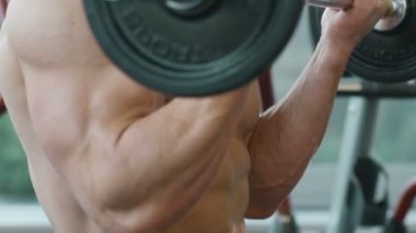 Beyaz tenli atletik adam kaslarını şişiriyor. Güçlü vücut geliştirici, karın kasları, trisepsleri, göğsü ve omuzları var. Fitness ve vücut geliştirme konsepti