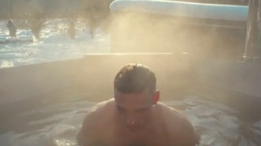 Yakışıklı bir adam, karlı bir kışta sıcak suda banyoda buharla yıkandı. Spor, sağlık ve sertleşme kavramı  