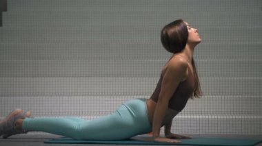 Jimnastik salonundaki spor salonundaki kaslarını esneten kadın. Spor fitness ve vücut geliştirme konsepti. Beyaz kız spor salonunda karın kası egzersizi yapıyor.