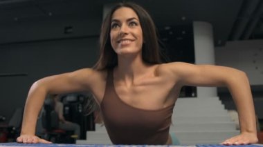 Spor salonunda şınav çeken fitness kadını. Beden eğitiminde göğüs ve omuzlar için egzersiz yapan güçlü bir vücut geliştirici. Fitness, vücut geliştirme ve egzersiz konsepti