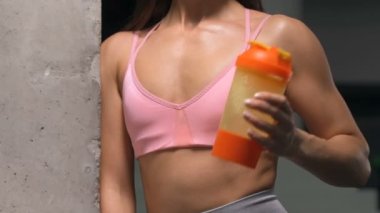 Spor salonunda spor salonunda spor salonundaki turuncu ve pembe karıştırıcıdan su içen kadın. Egzersiz yapan beyaz bir kız. Fitness, vücut geliştirme ve sağlık hizmeti kavramı.