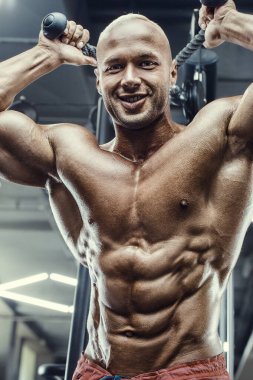 Vücut geliştirici yakışıklı güçlü atletik sert adam triceps kaslarını şişiriyor vücut geliştirme konsepti sağlıklı tasarım - kaslı fitness erkekler spor salonunda çıplak gövde egzersizleri yapıyor