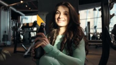 Spor salonunda spor salonunda spor salonundaki turuncu ve pembe karıştırıcıdan su içen kadın. Egzersiz yapan beyaz bir kız. Fitness, vücut geliştirme ve sağlık hizmeti kavramı. 