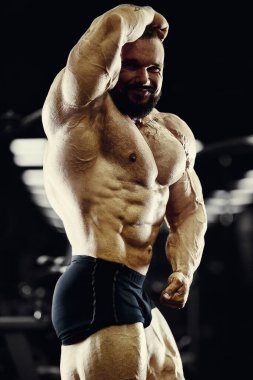 Vücut geliştirici yakışıklı güçlü atletik sert adam karın kaslarını şişiriyor kasları çalıştırıyor vücut geliştirme ve sağlıklı bir konsept geliştirme geçmişi var - kaslı fitness adamları spor salonunda çıplak gövde egzersizleri yapıyor.