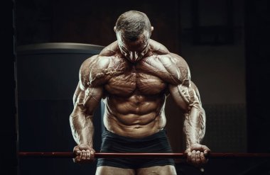 Vücut geliştirici kasları şişiriyor vücut geliştirme egzersizi yapıyor ve sağlıklı bir konsept geliştiriyor. Vücut geliştiren adamlar spor salonunda çıplak vücut egzersizleri yapıyor. Yakışıklı, güçlü, atletik sert adam.