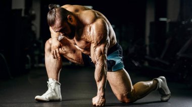 Güçlü atletik erkekler vücut geliştirme konusunda kas geliştiriyorlar. Kaslı vücut geliştirici yakışıklı erkekler spor salonunda çıplak gövde egzersizleri yapıyor.