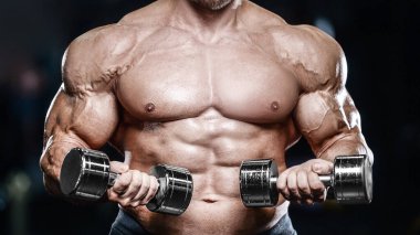 Vahşi seksi vücut geliştirme sporcusu kaslarını çalıştıran vücut geliştirme konsepti geliştiren sporcu. Spor salonunda çıplak vücut geliştirme egzersizleri yapan kaslı yakışıklı erkekler.