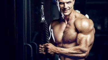 Formda bir adam spor salonunda kol kaslarını çalıştırıyor. Pazı egzersizi yapıyorum. Antrenmanda kasları kapat. Vücut geliştirme, fitness ve sağlık hizmeti kavramı.
