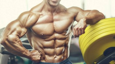 Spor salonunda karın kaslarını çalıştıran formda bir adam. Karın egzersizi şişiriyorum. Antrenmanda kasları kapat. Vücut geliştirme, fitness ve sağlık hizmeti kavramı.