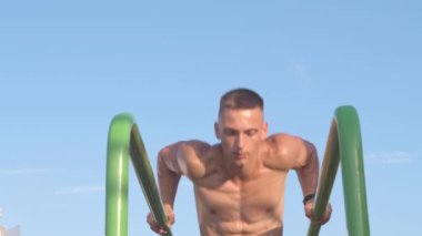 Paralel barlarda çiş yapan kaslı atletik genç adam. Spor ve sağlık konsepti 