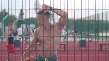 Atletik genç adam basketbol sahasında elinde bir topla dolaşıyor ve önüne bakıyor. Spor ve sağlık konsepti 